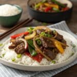 Sizzling Chinese pepper steak with onions on a plate.
