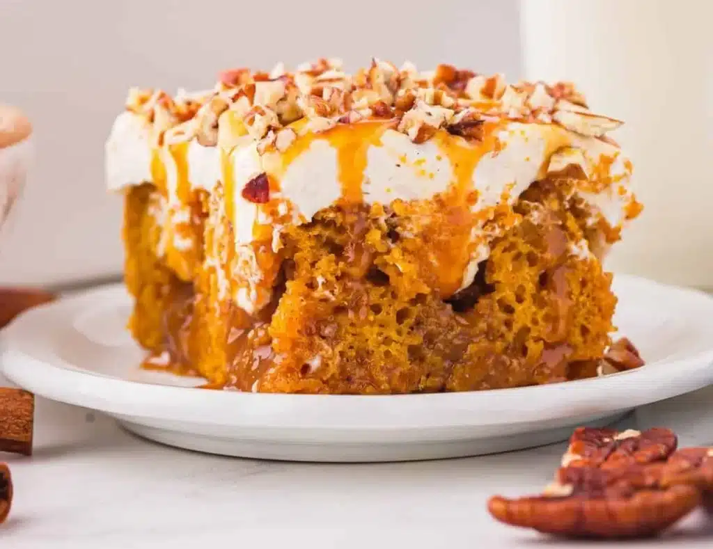 Delicious Pumpkin Poke Cake topped with cream and spices